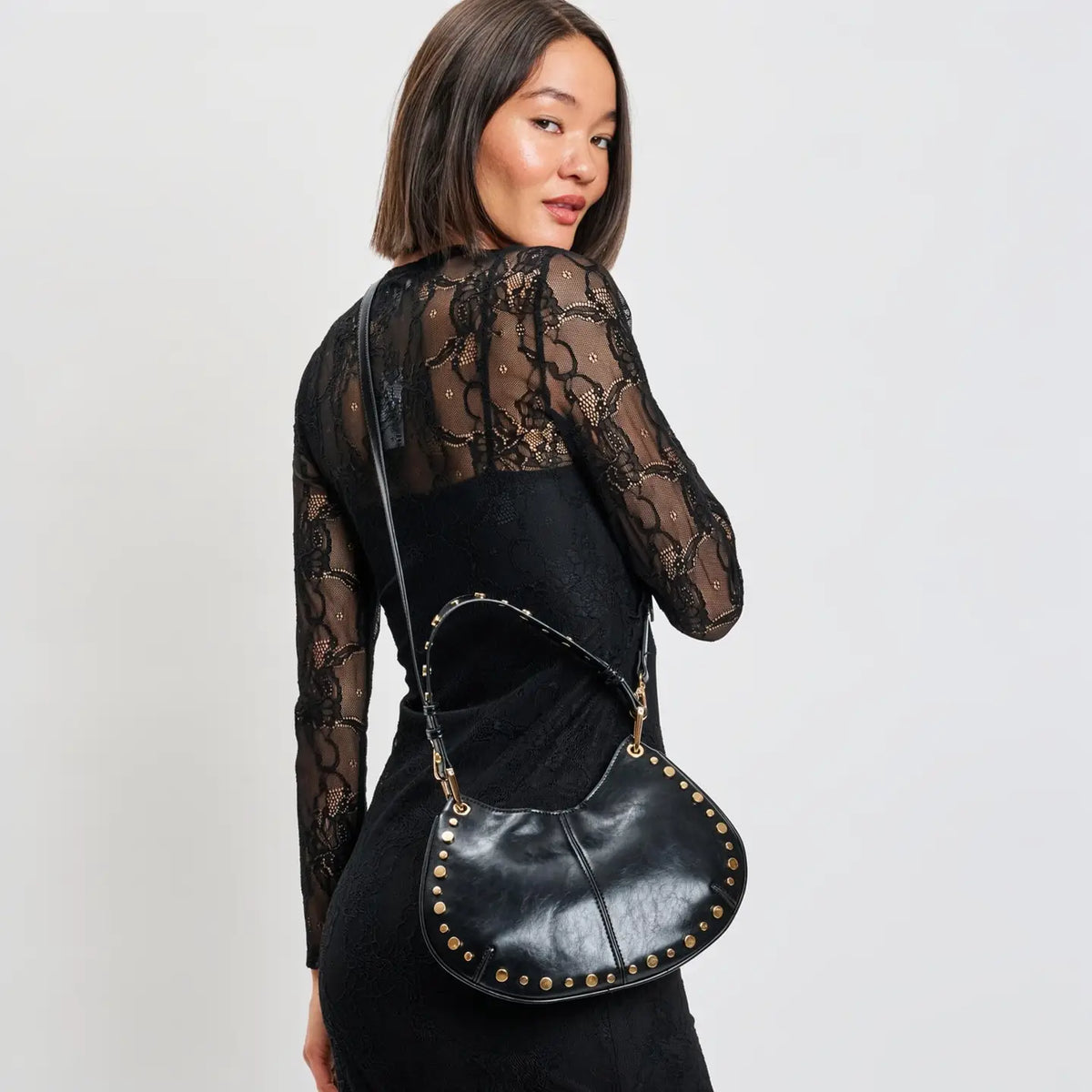 Rear view of model wearing black lace dress with Nova black studded shoulder bag