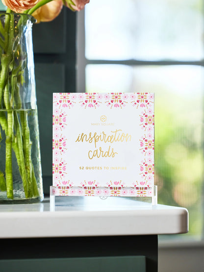 Mary Square Inspiration Cards block in acrylic stand on white table beside glass flower vase