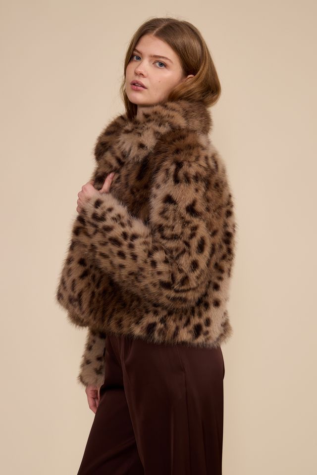 Model in brown leopard faux fur jacket side profile burgundy pants neutral background