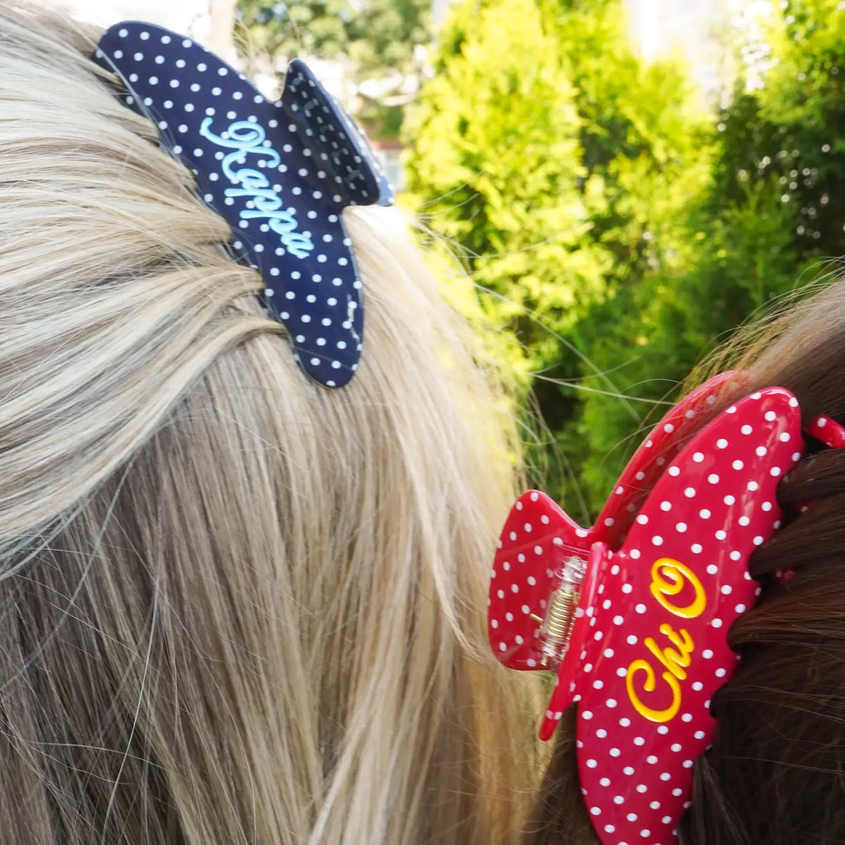 Two polka dot sorority hair claw clips, navy Kappa and red Chi O, worn outdoors